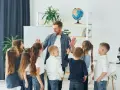 Nauczyciel z dziećmi świętuje koniec semestru. Wesoła klasa, która czeka na wystawienie ocen na 1 semestr.