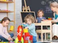 Opiekunka dziecięca z dziećmi buduje rakietę z klocków.