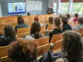 Wykład o przygotowaniu pedagogicznym dla psychologów. Studenci słuchają prelegentki przy tablicy interaktywnej.
