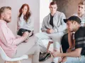 Grupa młodych ludzi na terapii. Terapeuta notuje, omawiając nowelizację Karty Nauczyciela.