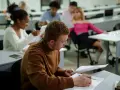 Studenci w sali wykładowej, skupieni na nauce. To dowód, że studia bez matury są możliwe i dają szansę na rozwój.