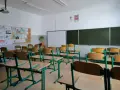 Pusta klasa szkolna z ławkami i krzesłami. Na ścianie tablica, projektor i dziecięce rysunki. Dziś odwołane zajęcia w szkołach.