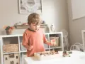 Chłopiec z zaciekawieniem bawi się piaskiem i muszelkami, co może być częścią zajęć korekcyjno kompensacyjnych.