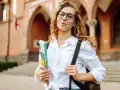 Studentka z okularami i zeszytami, gotowa do nauki. Jej klasyfikacja jako pilnej uczennicy jest oczywista.