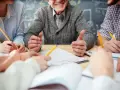 Uśmiechnięty nauczyciel w stanie nieczynnym, otoczony przez studentów piszących notatki.