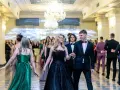 Młoda para w eleganckich strojach, ona w czarnej sukni, on w garniturze, idzie na bal studniówkowy.
