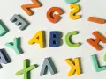 Kolorowe drewniane litery, idealne dla nauczyciela wychowania przedszkolnego, tworzą napis "ABC" i inne znaki.