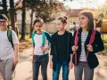 Grupa dzieci idzie razem, może planują wagary. Mają plecaki i wyglądają na podekscytowanych.