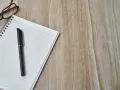 Notatnik z długopisem i okularami, gotowy do spisania opinii o uczniu.