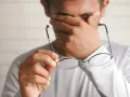 Zmęczony pracownik pociera oczy, trzymając okulary. Marzy o urlopie bezpłatnym zgodnie z kodeksem pracy.
