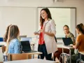 Nauczycielka wyjaśnia studentom, jak zostać nauczycielem, prowadząc lekcję w sali komputerowej.