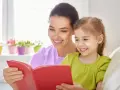 Uśmiechnięta mama czyta bajkę córce. To wspaniała opieka na dziecko 2 dni w tygodniu, pełna radości i wspólnych chwil.