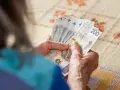 Dłonie liczą banknoty 200 zł. Zastanawiasz się, ile trzeba przepracować na 13 pensję?