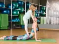 Mama i córka ćwiczą jogę, doskonaląc koordynację ruchową. Dziewczynka stoi na plecach mamy w pozycji kobry.