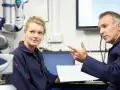 Młoda pracownica i starszy mężczyzna omawiają dokumentację techniczną. To część rutynowych badań okresowych pracowników.