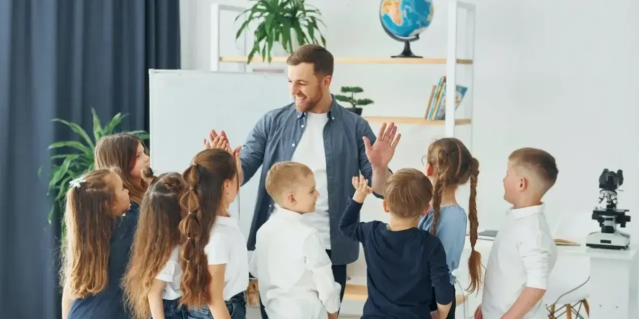Nauczyciel z dziećmi świętuje koniec semestru. Wesoła klasa, która czeka na wystawienie ocen na 1 semestr.