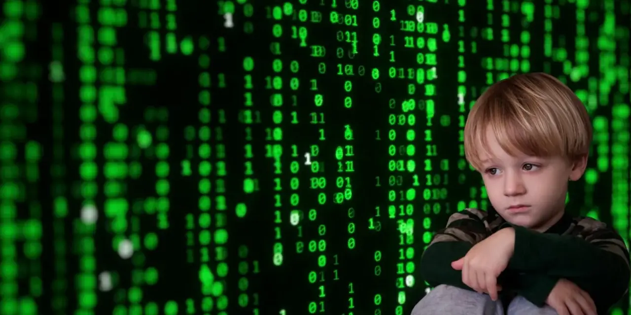 Smutny chłopiec siedzi przed ekranem z zielonym kodem, symbolizującym cyberprzemoc.
