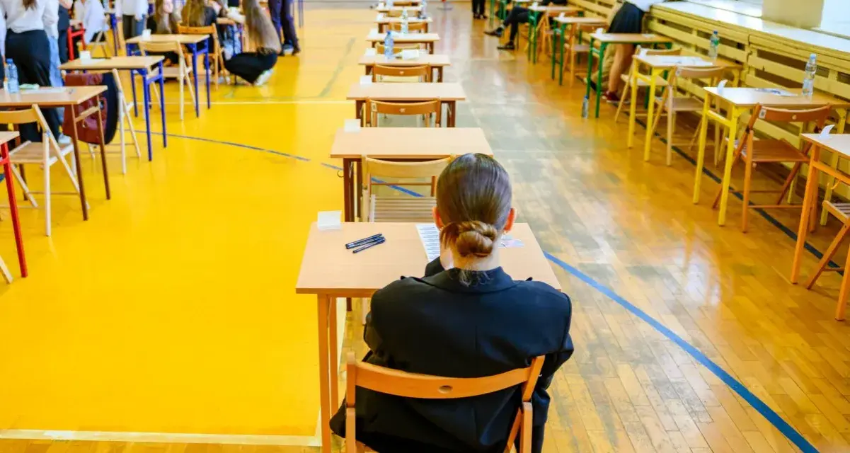 Uczniowie siedzą w ławkach, przygotowując się do egzaminu maturalnego. Atmosfera skupienia towarzyszy przyszłym maturzystom w drodze do matury 2026.