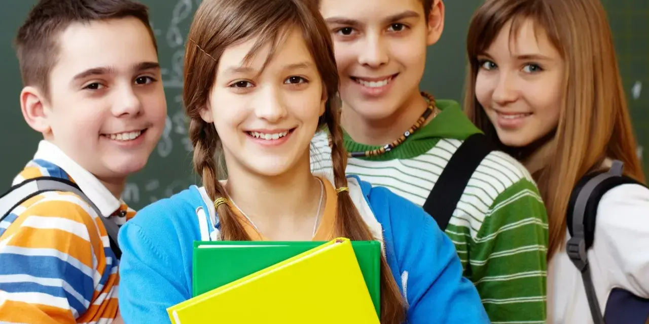 Uśmiechnięci uczniowie z podręcznikami, gotowi do nauki. Ich edukacja zdrowotna i program nauczania to klucz do przyszłości.