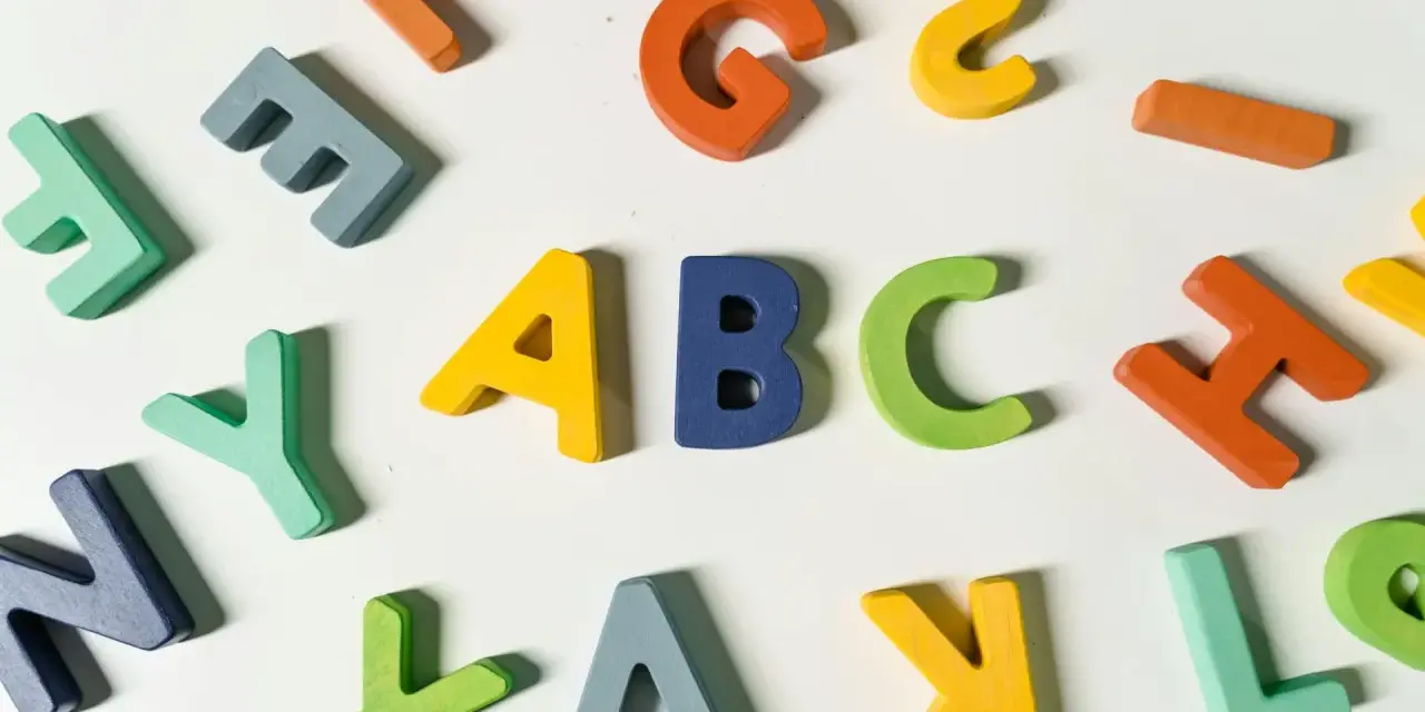 Kolorowe drewniane litery, idealne dla nauczyciela wychowania przedszkolnego, tworzą napis "ABC" i inne znaki.