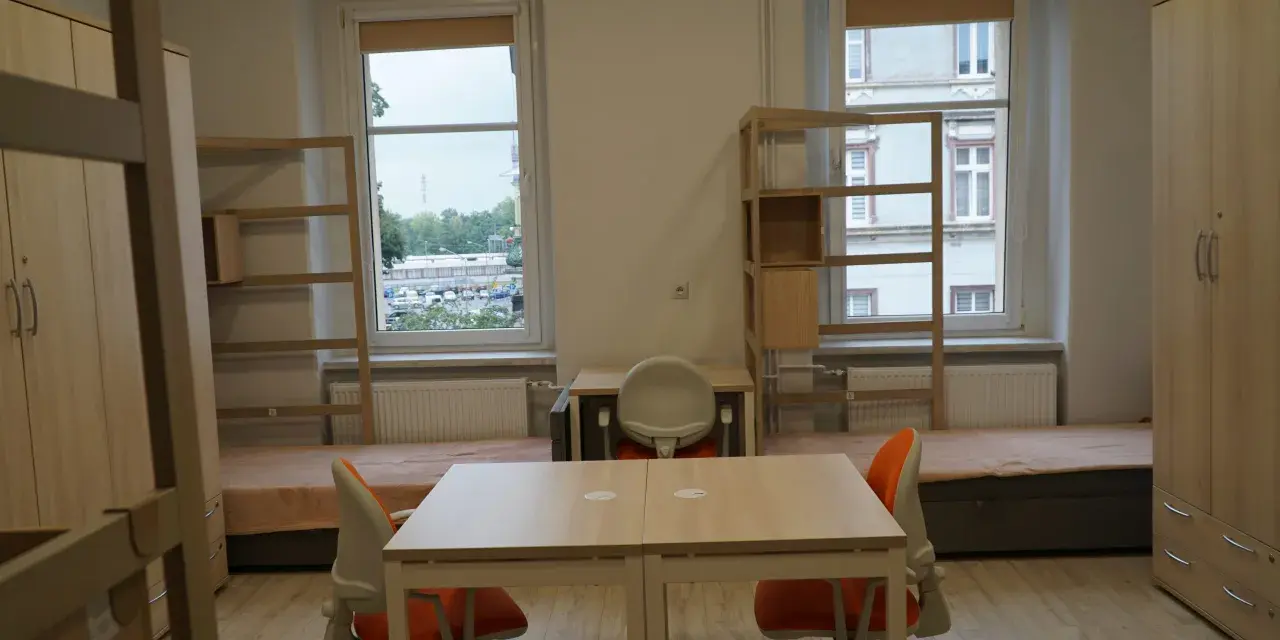 Pokój studencki, gdzie bursa co to? Dwa łóżka, biurka, szafy i regały.