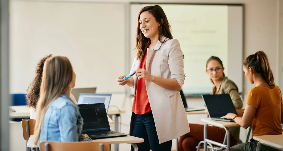 Nauczycielka wyjaśnia studentom, jak zostać nauczycielem, prowadząc lekcję w sali komputerowej.