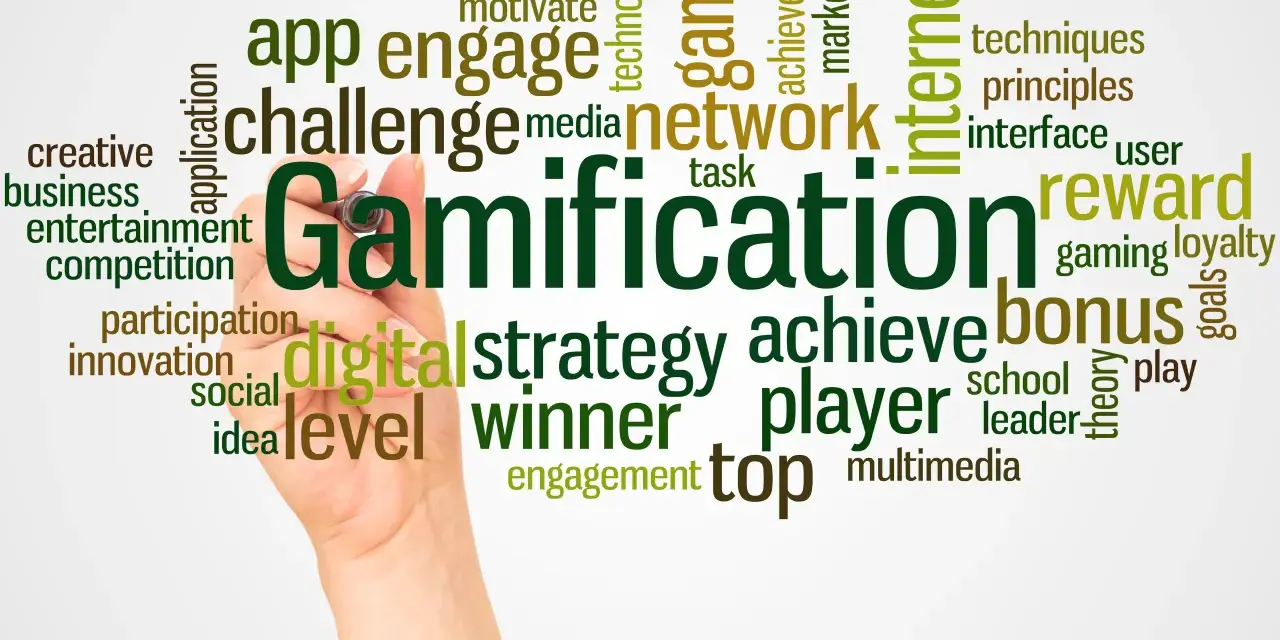 Ręka pisze słowo "Gamification" otoczone chmurą powiązanych terminów, takich jak "gra", "nagroda", "bonus", "strategia", "motywacja" i "sieć". Grywalizacja w akcji!