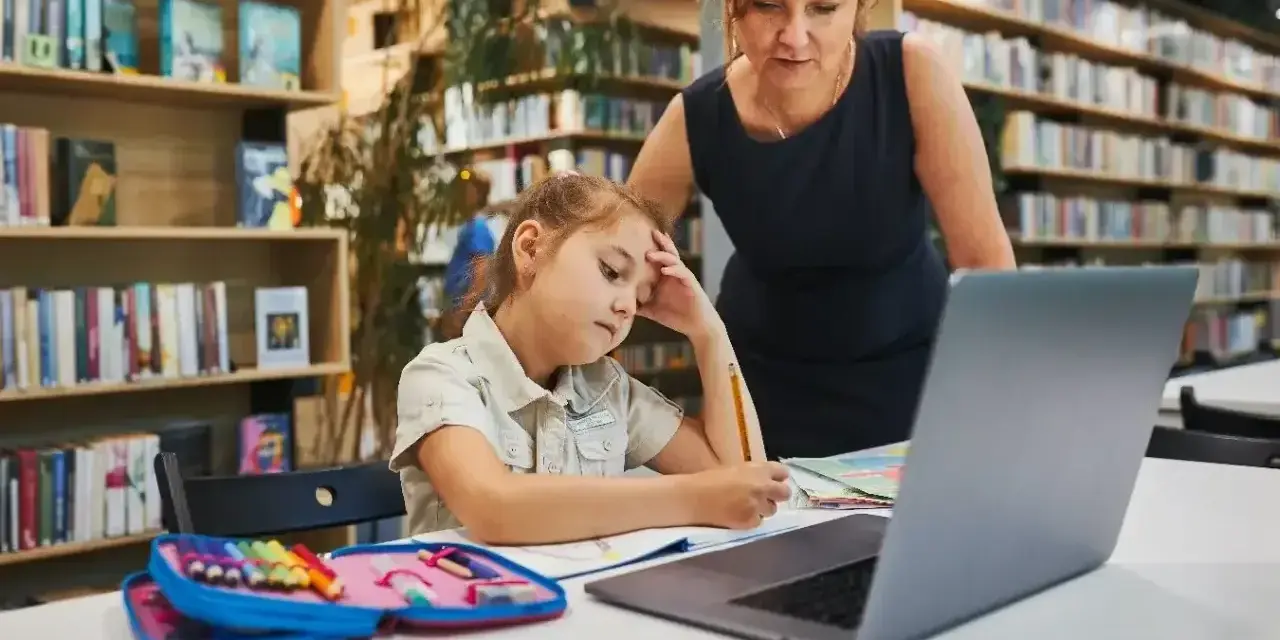Nauczycielka pomaga uczennicy z zadaniem. Dziewczynka ma trudności, potrzebuje status ucznia od zaraz.
