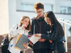 Trzech studentów dyskutuje o notatkach, zastanawiając się nad statusem ucznia a umową zlecenie.