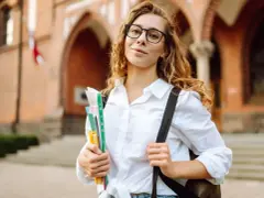 Studentka z okularami i zeszytami, gotowa do nauki. Jej klasyfikacja jako pilnej uczennicy jest oczywista.