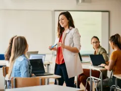 Nauczycielka wyjaśnia studentom, jak zostać nauczycielem, prowadząc lekcję w sali komputerowej.