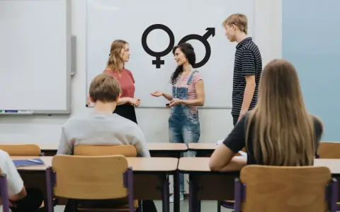 Lekcja edukacji seksualnej w klasie. Nauczycielka omawia symbole płci z uczniami.