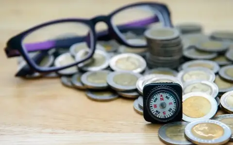 Okulary, monety i kompas symbolizują drogę do uzyskania dofinansowania do okularów.