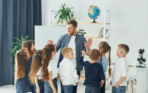 Nauczyciel z dziećmi świętuje koniec semestru. Wesoła klasa, która czeka na wystawienie ocen na 1 semestr.