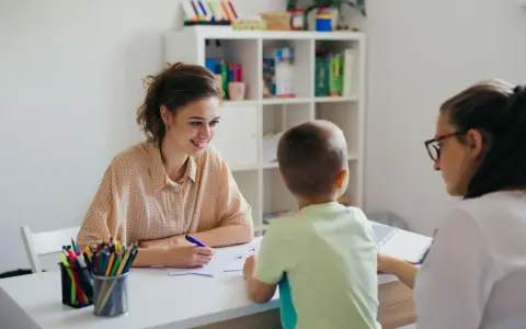 Uśmiechnięta nauczycielka omawia z rodzicami orzeczenie o potrzebie kształcenia specjalnego dla dziecka.