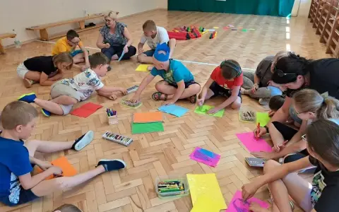 Dzieci klas 1-3 biorą udział w zabawach integracyjnych, rysując na kolorowych kartkach.