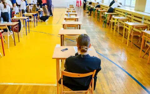 Uczniowie siedzą w ławkach, przygotowując się do egzaminu maturalnego. Atmosfera skupienia towarzyszy przyszłym maturzystom w drodze do matury 2026.