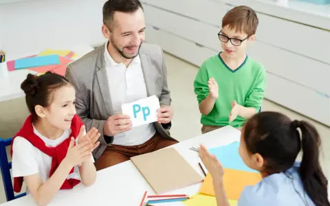 Nauczyciel pokazuje literę "Pp" podczas zebrania z rodzicami. Dzieci klaszczą, ucząc się alfabetu.