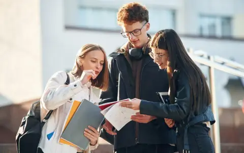Trzech studentów dyskutuje o notatkach, zastanawiając się nad statusem ucznia a umową zlecenie.