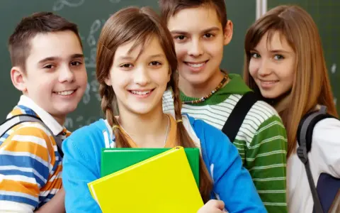 Uśmiechnięci uczniowie z podręcznikami, gotowi do nauki. Ich edukacja zdrowotna i program nauczania to klucz do przyszłości.