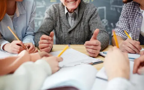 Uśmiechnięty nauczyciel w stanie nieczynnym, otoczony przez studentów piszących notatki.