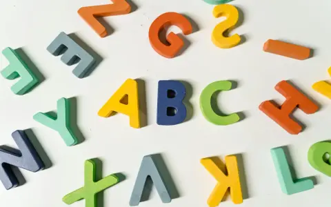 Kolorowe drewniane litery, idealne dla nauczyciela wychowania przedszkolnego, tworzą napis "ABC" i inne znaki.
