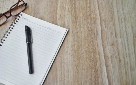 Notatnik z długopisem i okularami, gotowy do spisania opinii o uczniu.