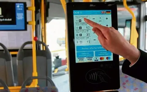 Ręka dotyka ekranu automatu biletowego w autobusie. Czy we Wrocławiu uczniowie jeżdżą za darmo? Tu kupisz bilet, sprawdzisz jego ważność i zapłacisz kartą.