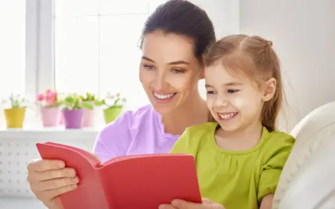 Uśmiechnięta mama czyta bajkę córce. To wspaniała opieka na dziecko 2 dni w tygodniu, pełna radości i wspólnych chwil.