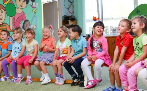 Uśmiechnięte dzieci siedzą w przedszkolu. Od ilu lat można tu uczęszczać?