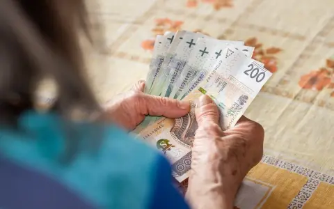 Dłonie liczą banknoty 200 zł. Zastanawiasz się, ile trzeba przepracować na 13 pensję?