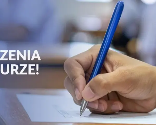 Dłoń pisze długopisem na arkuszu egzaminacyjnym. Napis "Powodzenia na maturze!" sugeruje, że to ważny moment dla osób z wykształceniem średnim.