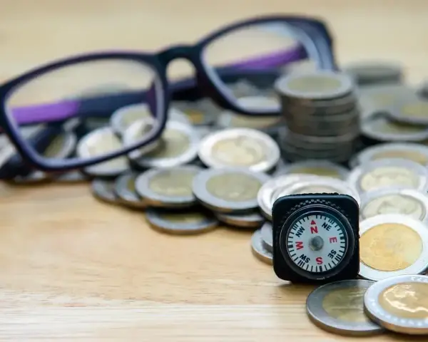 Okulary, monety i kompas symbolizują drogę do uzyskania dofinansowania do okularów.
