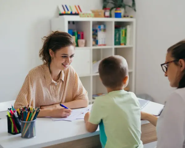 Uśmiechnięta nauczycielka omawia z rodzicami orzeczenie o potrzebie kształcenia specjalnego dla dziecka.